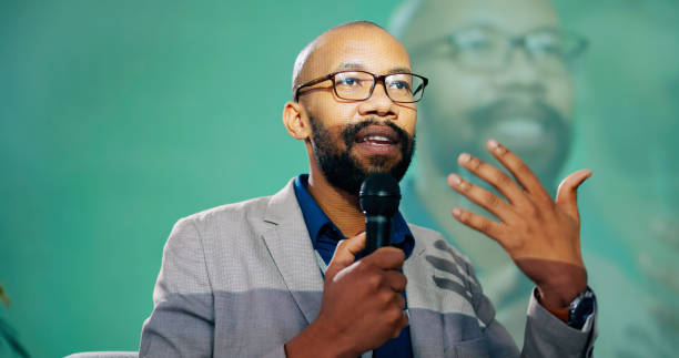 istock Conference, presentation or speech and public speaking man with microphone on stage for development seminar. Business, black man and workshop with motivational speaker person in corporate auditorium 2163778265