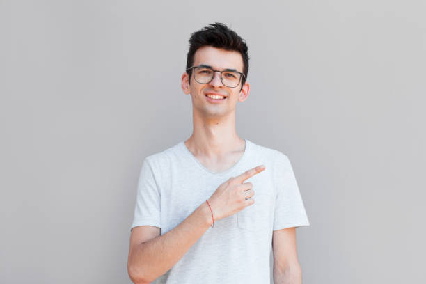 istock Handsome smiling man pointing away on gray background 2163787688