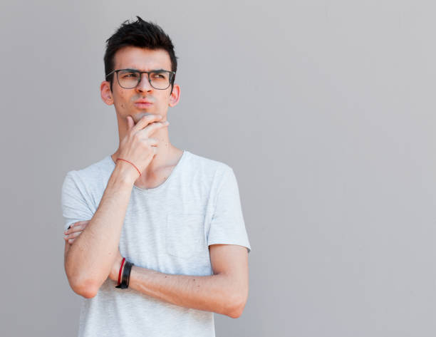 istock Young man with white shirt having doubts and with confuse face expression while scratching head on isolated grey background 2163789420