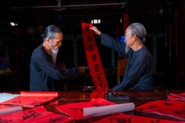 old scholars writing calligraphy at lunar new year. Calligraphy is a popular tradition during Tet holiday. Text in photo mean Happy New Year and Peace. Travel and holiday concept