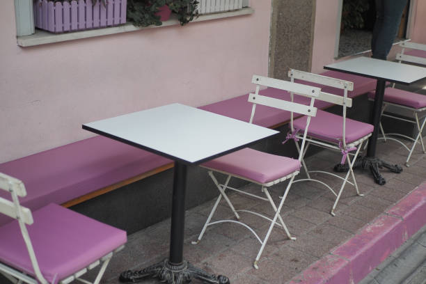 A cozy pink outdoor cafe seating area with white tables and chairs, inviting for a relaxing break.