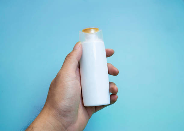 istock hand holding blank white shampoo bottle contaner on blue background 2163806095