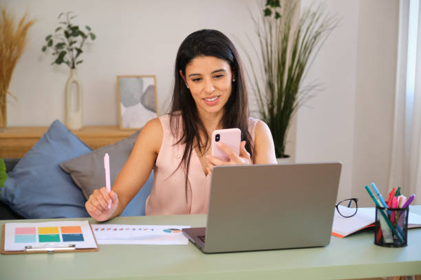 istock Young manager woman working from home using laptop and smartphone 2163808723