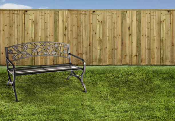 metal bench seat in a backyard with a fence