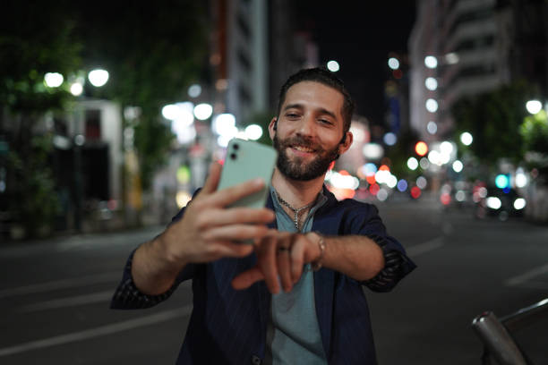 istock a tourist man taking selfies, smiling on his mobile smartphone when exploring the streets of tokyo at night 2163818043