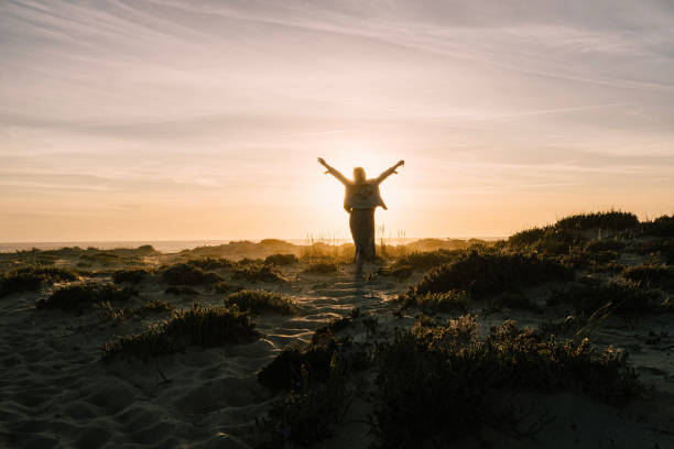 Young woman explores headland at sunset