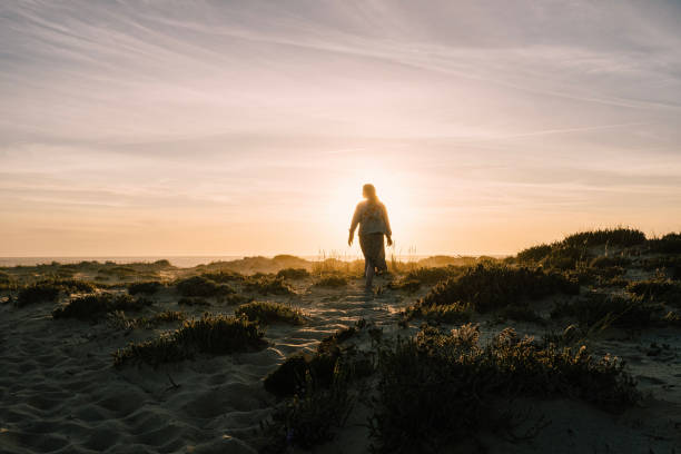 Young woman explores headland at sunset
