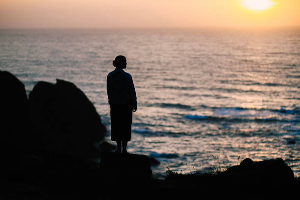 Young woman relaxes on rocky shoreline, Rogil