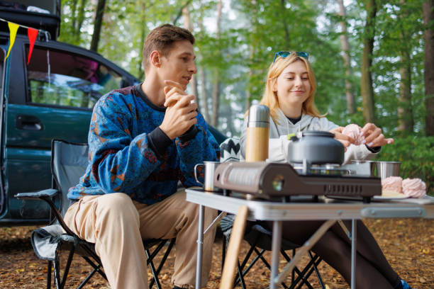 istock Young Couple Enjoying Marshmallow Snack by Minivan in Nature 2163824029