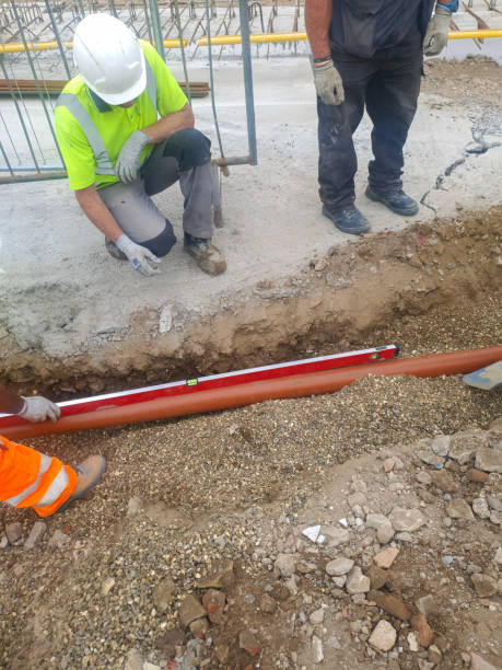 istock Construction worker installing drainage pipe in a trench at a building site. Infrastructure development concept. 2163835936