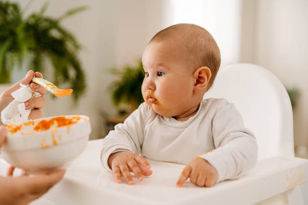 istock Mother feeding her baby with her first meal 2163837606