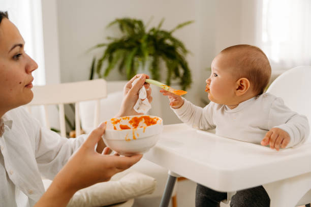 istock Mother feeding her baby with her first meal 2163837650