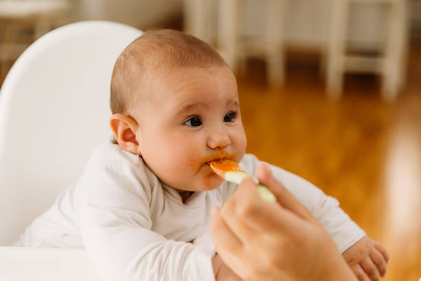 istock Mother feeding her baby with her first meal 2163837680