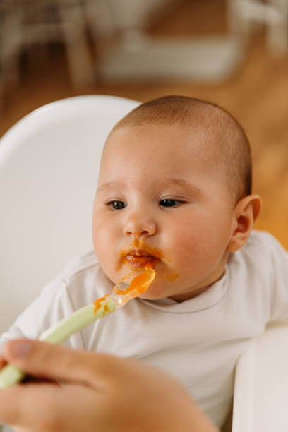 istock Mother feeding her baby with her first meal 2163837735
