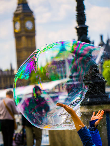 London, UK - May 1, 2016: A view of the Thames and London skyline looking North East and showing St Pauls cathedral. In the foreground are tourists and soap bubbles created by a street entertainer.