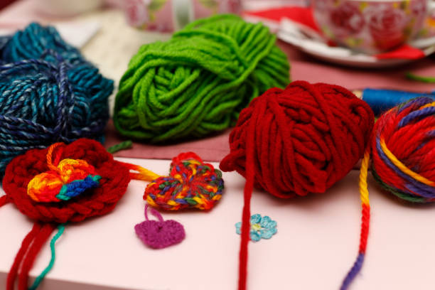 Woman’s hands showing a crocheted brooch and a sewing needle