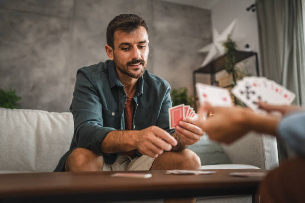 istock Serious man sit on sofa and play card and think about the next move 2163846187
