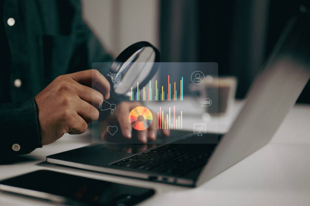 istock Person using a magnifying glass to examine data visualizations on a laptop. It represents the importance of detailed analysis and scrutiny in data-driven decision-making processes 2163849418