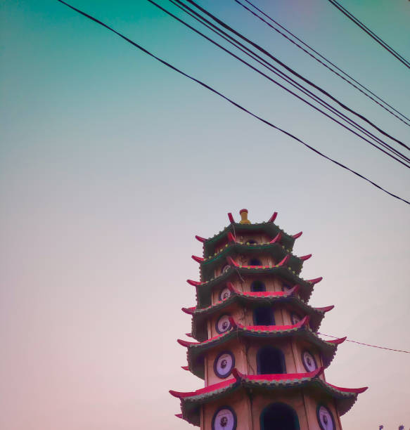 A temple tower against the backdrop of the morning sky in shades of blue pink purple and some hanging electric wires
