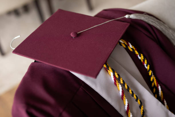 A overhead view of a graduation cap and diploma with a 2025 charm on a yellow tassel.
