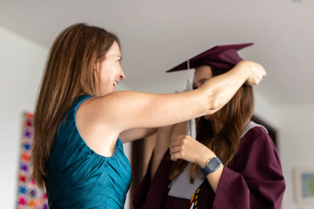 istock Mother helping her graduated daughter get dressed before graduation ceremony 2163863678
