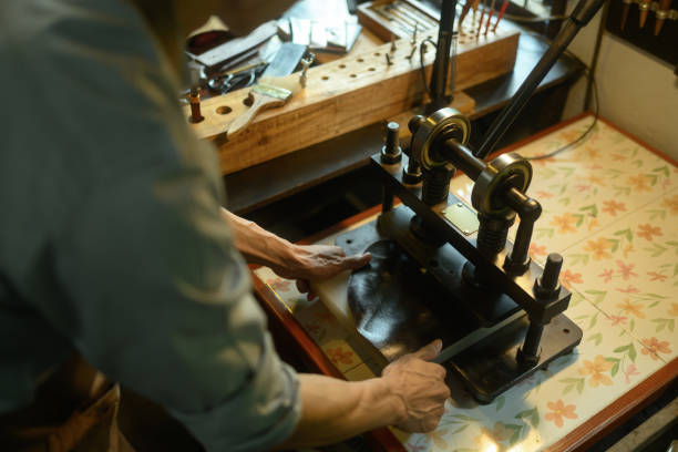 istock Leather craftsman using a manual rolling machine working on a leather project in his local workshop 2163870941