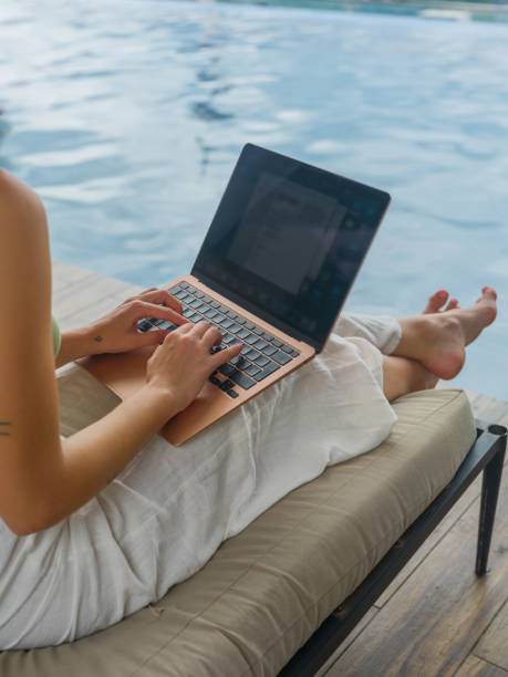istock Woman working with laptop sitting near the pool during workation 2163871105