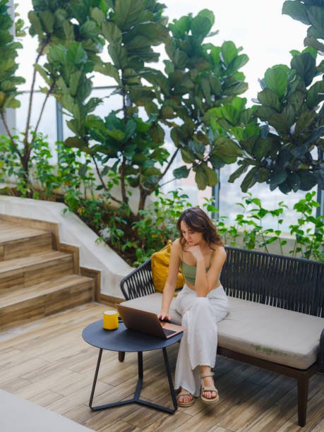 istock Woman working with laptop sitting on rooftop patio 2163871138