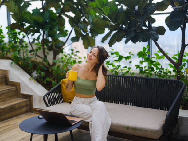 istock Woman working with laptop sitting on rooftop patio 2163871259