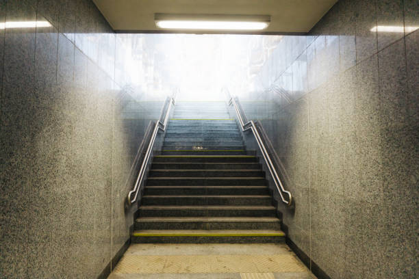 istock Underground pedestrian tunnel under train tracks with a bright end. Illuminated passageway leading to stairs. 2163880323