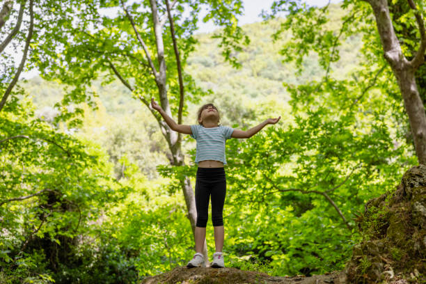 Little girl enjoying nature in green forest