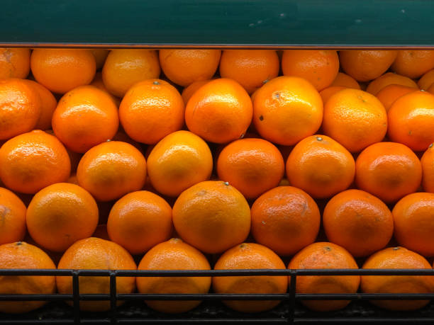 fresh ripe oranges neatly stacked in a grocery store display