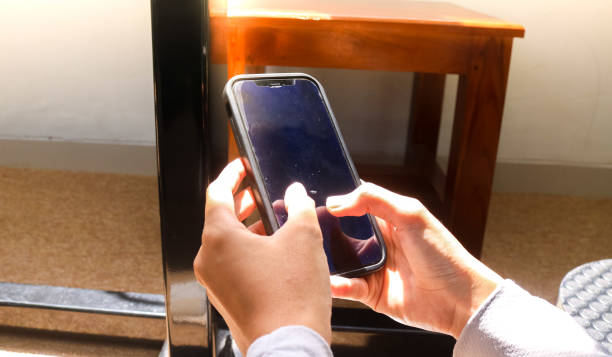 istock Woman's hand holding and touching mobile phone screen with two hands, mobile phone and aesthetic sunlight, girls using mobile phone in hand close up, technology and business concept background. 2163886907