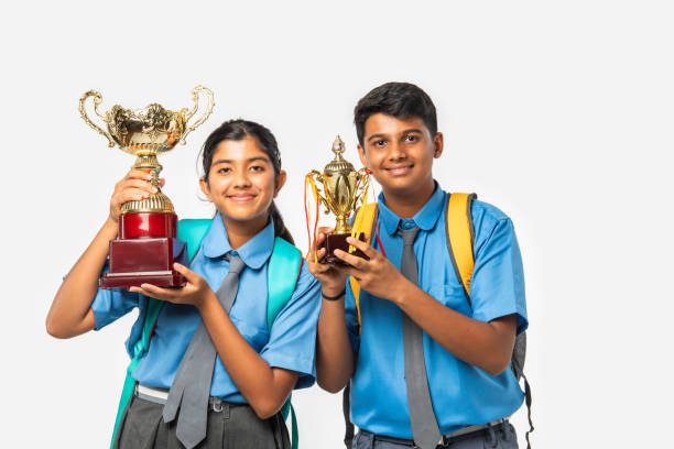 istock Two Indian Asian School students in uniform with books and backpacks, using or pointing at laptop 2163888944