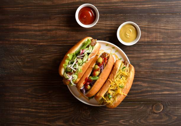 istock Hot dogs loaded with assorted toppings on wooden background 2163896896