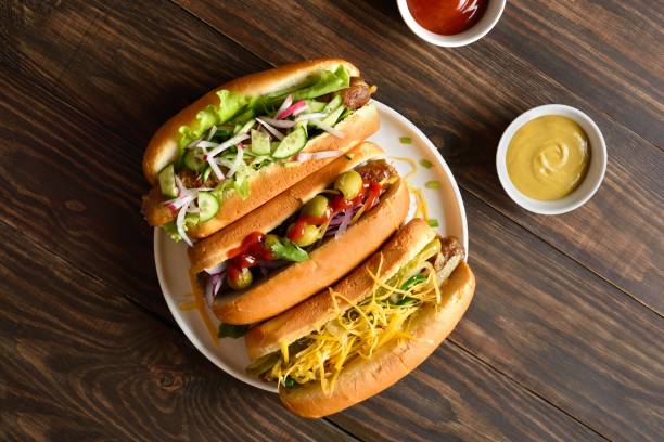 istock Hot dogs loaded with assorted toppings on wooden background 2163896904