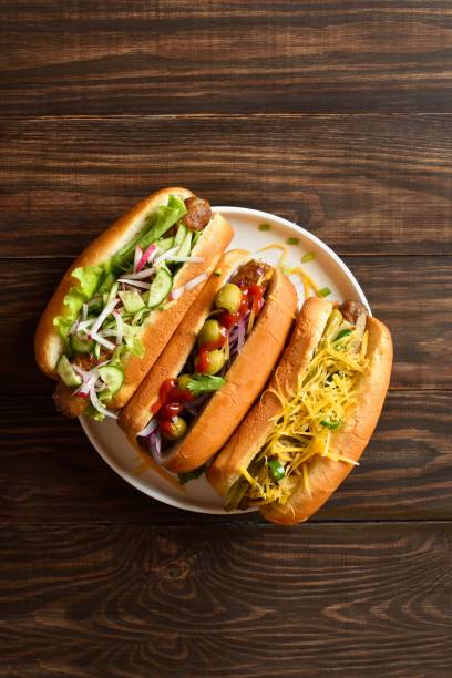 istock Hot dogs loaded with assorted toppings on wooden background 2163896948