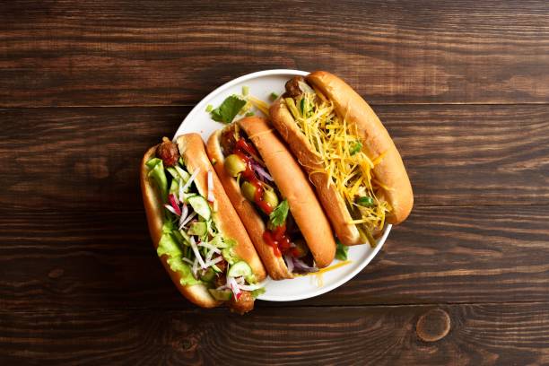 istock Hot dogs loaded with assorted toppings on wooden background 2163896954