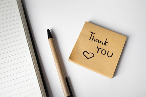 istock Sticky note with handwritten phrase thank you on white background with pen and notebook 2163898477