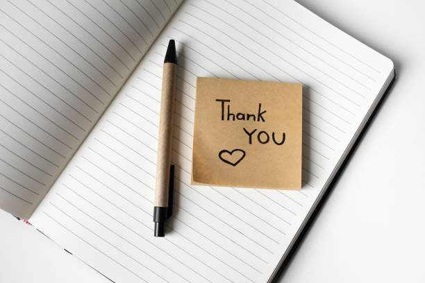 istock Sticky note with handwritten phrase thank you on a notebook with pen top view 2163898478