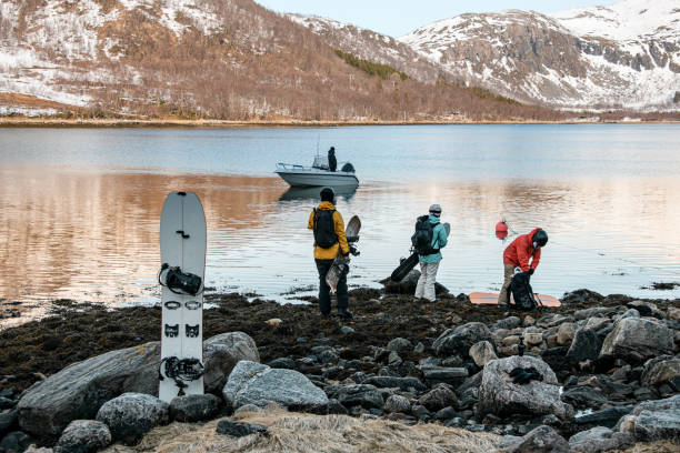 istock Three splitboarders stand on a rocky shore, holding their splitboards in their hands and waiting for a boat to come to shore 2163899073