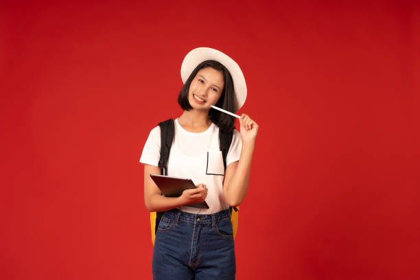 istock Diligence and determination to study to develop the education sector by a short-haired Asian female student using a laptop and pen to find knowledge, photographed in a studio with a red background. 2163900368