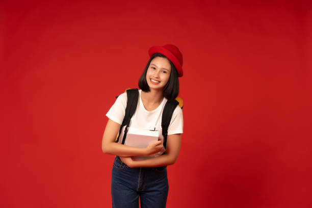istock The red studio background reflects the Asian school girl's eagerness to learn, representing her commitment to academic excellence and personal development, holding books and a school bag. 2163900503