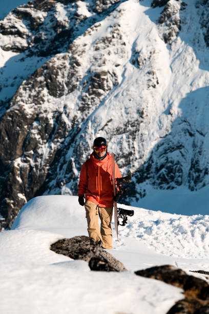 istock Skier in an orange jacket and goggles walks through the snow, carrying his split board 2163901096