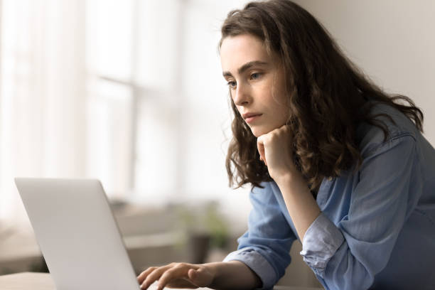 Serious young woman search information on internet use laptop
