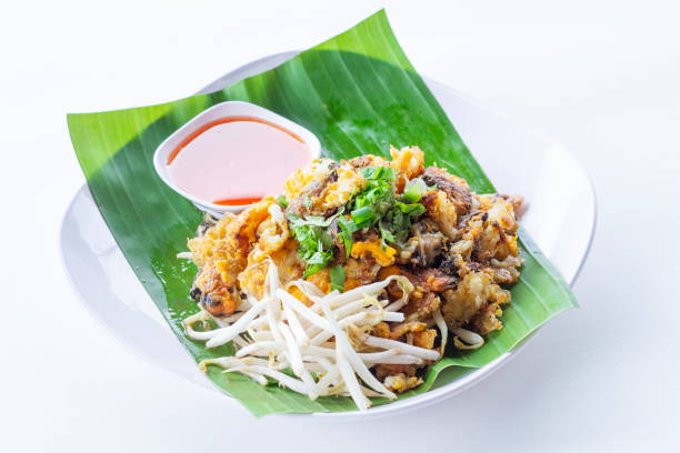 Thai-style fried Mussels are a popular one-dish meal. Made with mussels and batter that are fried until crispy. Place the plate with banana leaves on a white plate, isolate and white background los mejillones fritos al estilo tailandés son una comida popular de un solo plato. elaborado con mejillones y rebozados que se fríen hasta que estén crujientes. coloque el plato con hojas de plátano sobre un plato blanco, aislado y fondo blanco