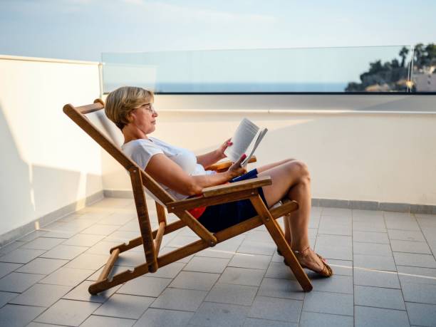 Photo of a couple enjoying hot summer day on the beach, while woman is reading the book, man is sunbathing
