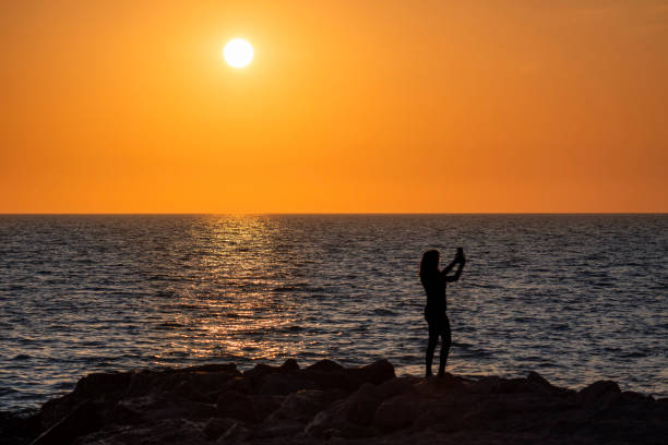 Woman photographing sunset on Albinia beach