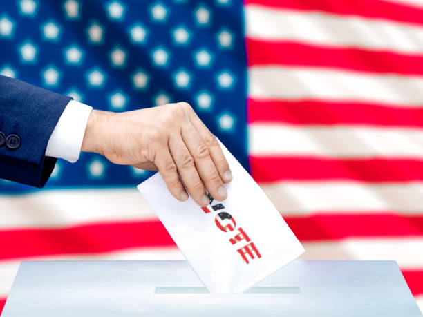 istock Hand Placing Ballot into Voting Box with American Flag 2163923363