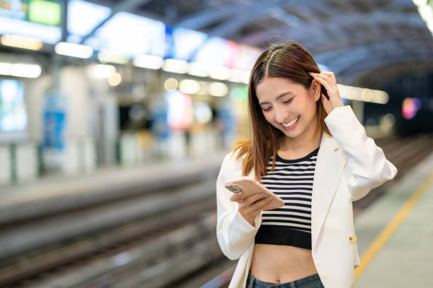 istock Young asian woman using smartphone application navigate location destination while travel by train. Asian female with cell phone standing near railway platform in train station. 2163923799